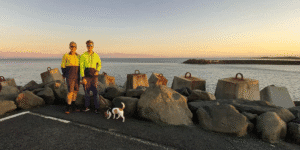 Photo of Brad and Toby Woolcott at the end of Ballina North Wall, River in the background, Jack Russel dog in foreground. Photo taken in 2018 by Angela Wooloctt.
