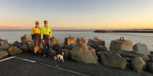 Brad and Toby Woolcott on Ballina North Wall 2023, river in the background. Jack Russel on a lead.